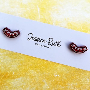 Könnte beinhalten: Ein Paar rote Glitzer-Ohrringe in Form eines Hotdogs. Die Ohrringe befinden sich auf einer weißen Karte mit dem Text "Jessica Ruth Creations".