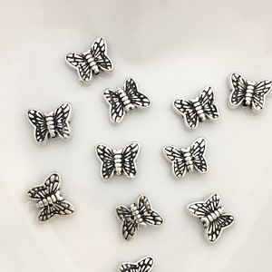 May include: Silver butterfly charms with intricate details. These charms are perfect for jewellery making, scrapbooking, and other craft projects.
