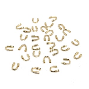 May include: A scattering of gold-toned metal crimp beads, designed for use in jewellery making.