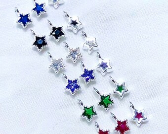 May include: Assortment of silver star-shaped charms with various colored gemstones. The charms have a loop at the top for attaching to jewelry or other crafts.