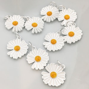 May include: Nine silver daisy charms with yellow centers. The charms are all the same size and shape, and they are perfect for adding a touch of whimsy to jewelry or crafts.