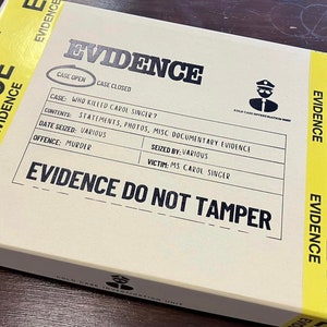 May include: A brown cardboard box with yellow tape labeled "EVIDENCE" on all sides. The box has a black label with the text "CASE OPEN CASE CLOSED" and details about a case: "WHO KILLED CAROL SINGER?"  "STATEMENTS, PHOTOS, MISC DOCUMENTARY EVIDENCE"  "VARIOUS"  "MURDER"  "VARIOUS"  "MS CAROL SINGER"  "EVIDENCE DO NOT TAMPER".