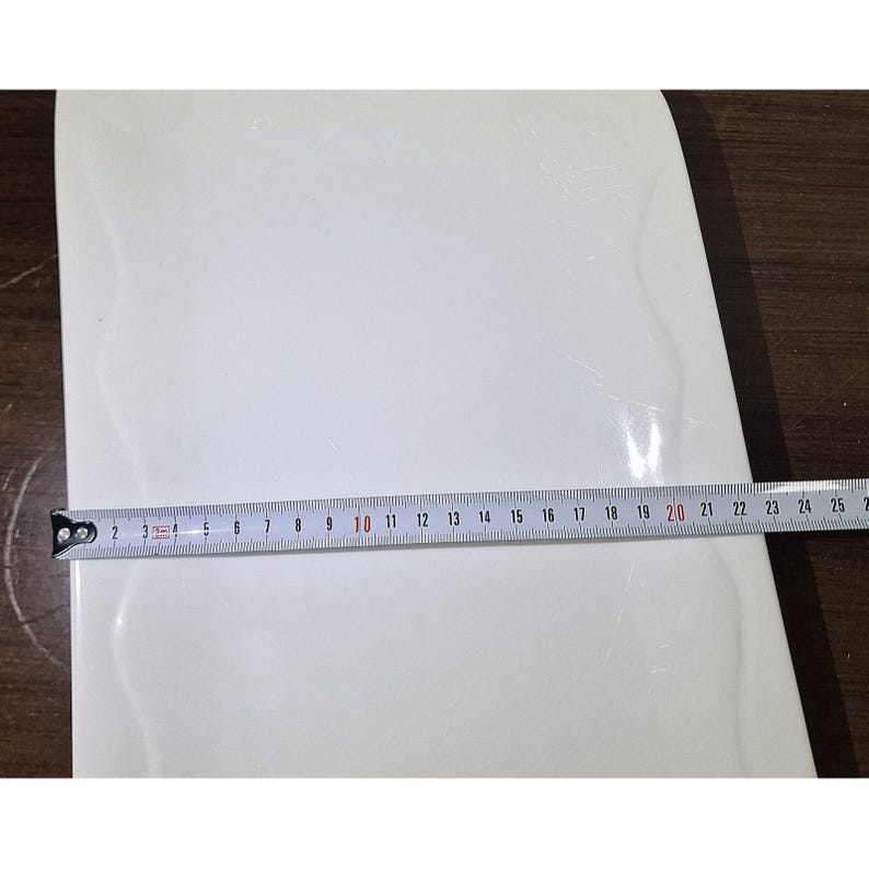 Puede incluir: Un objeto blanco y curvado con una cinta m&eacute;trica colocada encima. La cinta muestra una medida de aproximadamente 50 cm. El objeto parece ser parte de un elemento m&aacute;s grande, posiblemente un componente de mueble o un art&iacute;culo para el hogar.