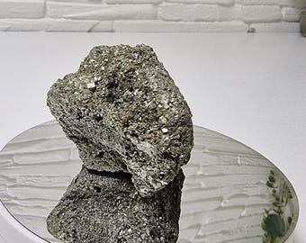 May include: A raw, metallic pyrite mineral specimen with a jagged, crystalline surface texture. The stone displays a natural, brassy gold color with reflective, cubic facets throughout its irregular, chunky, and multi-dimensional rock formation.