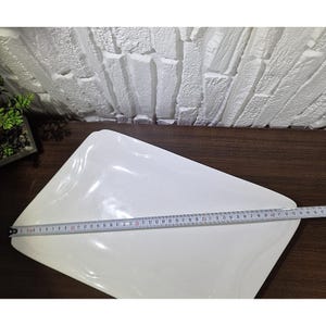 Puede incluir: Una fuente blanca rectangular con esquinas redondeadas. Una cinta m&eacute;trica se coloca sobre la fuente, indicando una longitud de aproximadamente 45 cm. La fuente est&aacute; sobre una superficie de madera marr&oacute;n oscuro.