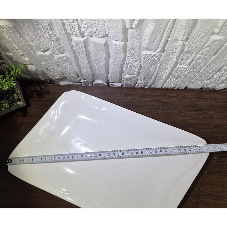 Puede incluir: Una fuente blanca rectangular con esquinas redondeadas. Una cinta m&eacute;trica se coloca sobre la fuente, indicando una longitud de aproximadamente 45 cm. La fuente est&aacute; sobre una superficie de madera marr&oacute;n oscuro.