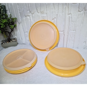 Könnte beinhalten: Drei gelbe und beige Kunststoff-Lebensmittelbehälter. Die Behälter haben eine runde Form mit Deckeln. Ein Behälter hat einen geteilten Innenraum. Die Deckel sind beige und die Böden sind gelb.