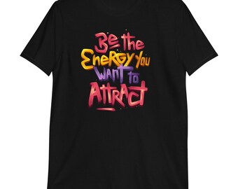 May include: Black t-shirt with the text "Be the Energy You Want to Attract" in a colorful, graffiti-style font.