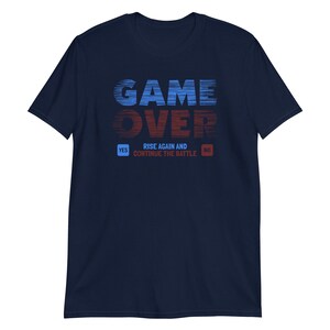 May include: Navy blue t-shirt with a blue and red graphic that says "GAME OVER" with a blue and red button that says "YES" and "NO" below the graphic. The text below the buttons says "RISE AGAIN AND CONTINUE THE BATTLE".