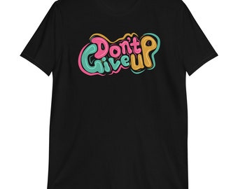 May include: Black t-shirt with the words "Don't Give Up" in a colorful, bubble-style font. The text is outlined in pink, teal, and yellow, creating a vibrant and eye-catching design. The shirt is made of a soft material.