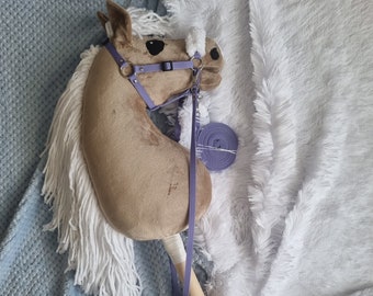 May include: A brown and white rocking horse with a purple bridle and reins. The horse is lying on a blue and white fluffy blanket.