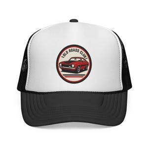 Pode incluir: Um boné trucker branco e preto com um gráfico circular no painel frontal. O gráfico mostra um carro antigo vermelho com faixas de corrida pretas e o texto OLD ROADS CLUB em uma fonte escura e em negrito, cercado por uma borda circular.