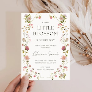 Może przedstawiać: Zaproszenie na baby shower z motywem kwiatowym. Zaproszenie zawiera tekst "A Sweet Little Blossom is on Her Way!" oraz szczegóły wydarzenia. Projekt przedstawia różowe i białe kwiaty.
