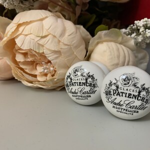 Puede incluir: Dos pomos de cer&aacute;mica blanca con letras negras que dicen "Glaces De Patiences Andre Cartier Montpellier Specialite".
