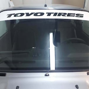 May include: A white windshield banner with black text that reads "TOYO TIRES".