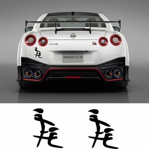 Puede incluir: Un coche deportivo Nissan GT-R blanco con detalles negros y una calcomanía negra en el parachoques trasero que dice "走  走".