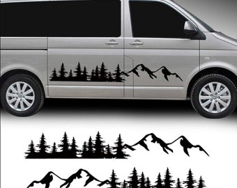 May include: Black vinyl decal of a mountain and forest scene. The decal is applied to the side of a silver van. The design features silhouetted pine trees and mountain peaks, creating a nature-inspired aesthetic.
