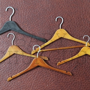 May include: Five hangers, four are wooden and one is black plastic. The wooden hangers are all different sizes and shapes.