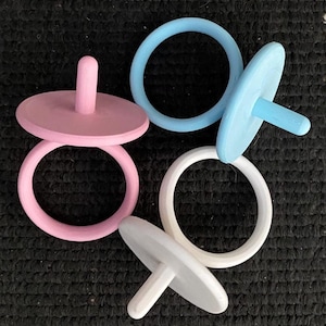 May include: Four wooden spinning tops with rings. Two tops are pink, one is blue, and one is white.