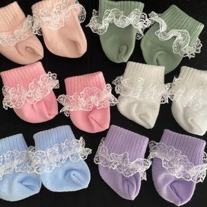 May include: Ten pairs of baby socks with lace trim in various colors, including pink, white, blue, green, and purple.