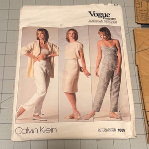 May include: A Vogue Patterns American Designer sewing pattern envelope for Calvin Klein, number 1669. The front displays three garment variations: a cardigan with trousers, a short-sleeved top with a skirt, and a strapless jumpsuit with a floral pattern.