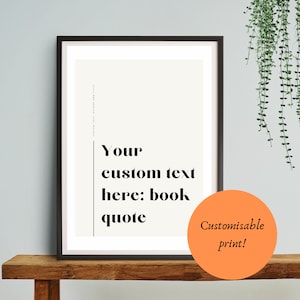 Może przedstawiać: Czarny obraz w ramie z białym tłem i czarnym tekstem, który brzmi "Your custom text here: book quote". Obraz stoi na drewnianej półce, a w tle wisi zielona roślina. W prawym dolnym rogu obrazu znajduje się pomarańczowe koło z tekstem "Customisable print!"