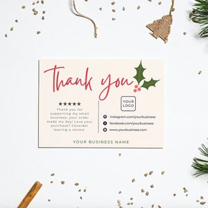 May include: A pink thank you card with a holly sprig and red berries. The card says "Thank you" in red script and includes a five-star rating, a place for your logo, and social media links. The text reads: "Thank you for supporting my small business, your order made my day! Love your purchase? Consider leaving a review. YOUR BUSINESS NAME"
