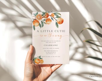 May include: A light pink baby shower invitation with a watercolor illustration of orange blossoms and the text "A Little Cutie is on the way". The invitation includes the name "Charmaine", the date "June 7th, 2023 at 2:00pm", the location "The Smith Residence, 127 Beach Blvd, San Diego, CA", and the RSVP information "RSVP to Jane at 555 399 1234".