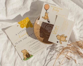 Puede incluir: Una invitación a una fiesta de bienvenida al bebé con temática de Winnie the Pooh con un patrón de panal y el texto "Un pequeño conejito está en camino". La invitación incluye el nombre del anfitrión de la fiesta de bienvenida al bebé, la fecha, la hora y la ubicación. También hay una tarjeta separada para una rifa de pañales y una tarjeta con el texto "Libros para bebé".