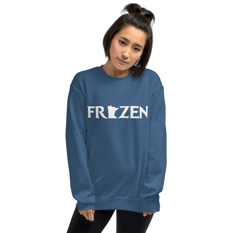 Puede incluir: Una sudadera azul con la palabra "FROZEN" en letras blancas, con el contorno del estado de Minnesota reemplazando la "O".