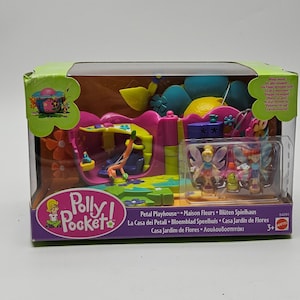 Może przedstawiać: Zestaw do zabawy Polly Pocket Petal Playhouse w przezroczystym plastikowym pudełku. Zestaw do zabawy przedstawia różową i żółtą konstrukcję o tematyce kwiatowej z miniaturowymi figurkami. Pudełko zawiera tekst w wielu językach.