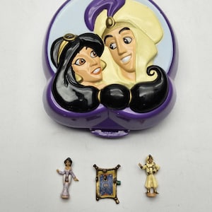 Può includere: Un playset viola a tema Aladdin con un coperchio incernierato con Jasmine e Aladdin. Include figurine in miniatura di Jasmine, Aladdin e un tappeto magico. Il set è un giocattolo da collezione.