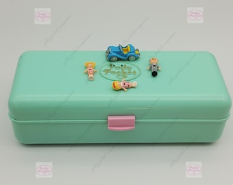 May include: A teal blue Polly Pocket compact case with a pink latch. The case is open and shows a blue car, two dolls, and a man figure. The case has a gold Polly Pocket logo on the front.