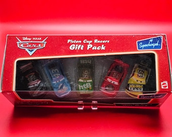 May include: A boxed set of Disney Pixar Cars Piston Cup Racers. The gift pack contains five toy race cars in various colours, each with unique designs and the text "Supercharged". The box is red with the Cars logo.