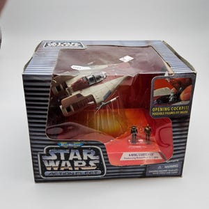 May include: A boxed Micro Machines Star Wars Action Fleet A-Wing Starfighter toy. The box features the Star Wars logo and the text "OPENING COCKPIT! POSEABLE FIGURES FIT INSIDE." The toy includes two small figures.