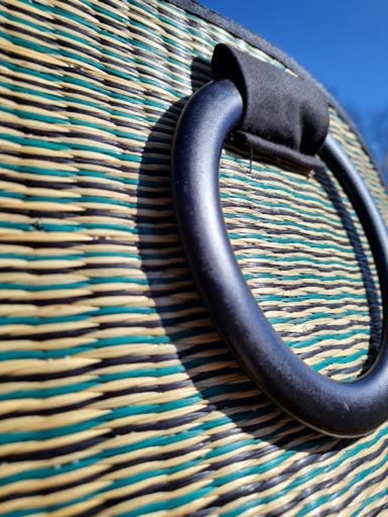 Peut inclure: Un sac tiss&eacute; avec une poign&eacute;e noire. Le sac est fait de mat&eacute;riaux naturels et pr&eacute;sente un motif ray&eacute; dans les tons de vert, marron et beige.