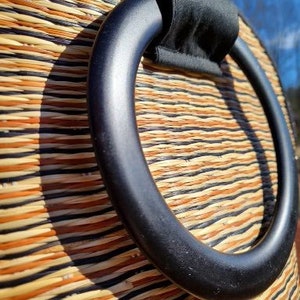 Peut inclure: Gros plan sur une poign&eacute;e tiss&eacute;e noire sur un sac tiss&eacute; naturel. La poign&eacute;e est une boucle &eacute;paisse et arrondie avec une doublure en tissu noir.
