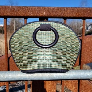 Peut inclure: Un sac &agrave; main tiss&eacute; vert et noir avec une poign&eacute;e noire. La poign&eacute;e est un grand anneau.