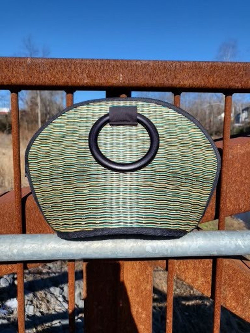 Peut inclure: Un sac &agrave; main tiss&eacute; vert et noir avec une poign&eacute;e noire. La poign&eacute;e est un grand anneau.