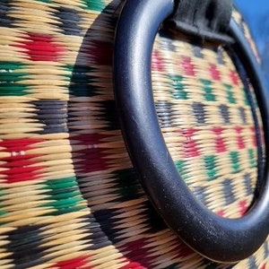 Peut inclure: Gros plan sur un sac tiss&eacute; avec une poign&eacute;e noire. Le sac est fait de mat&eacute;riaux naturels et pr&eacute;sente un motif g&eacute;om&eacute;trique color&eacute;.