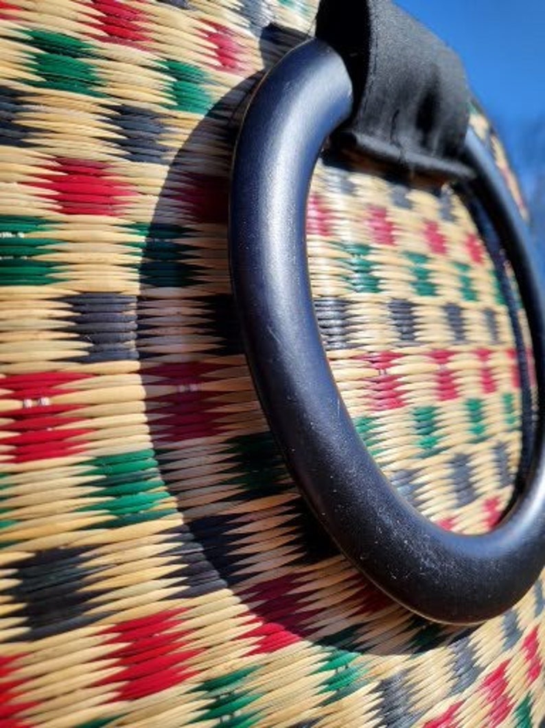 Peut inclure: Gros plan sur un sac tiss&eacute; avec une poign&eacute;e noire. Le sac est fait de mat&eacute;riaux naturels et pr&eacute;sente un motif g&eacute;om&eacute;trique color&eacute;.