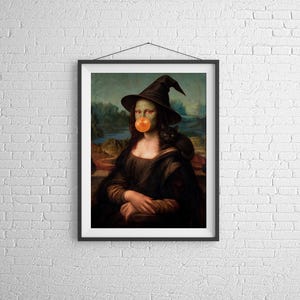 Puede incluir: Una impresión de arte mural enmarcada que muestra una figura de piel verde con un sombrero de bruja negro puntiagudo y soplando una gran burbuja naranja. Un pequeño gato negro está sentado sobre el hombro, con un fondo de paisaje.