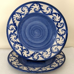 May include: Two blue and white ceramic plates with a swirling design. The plates have a white background with a blue floral pattern around the edge.