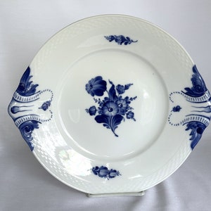 May include: A white porcelain serving platter with blue floral designs and decorative handles. The platter has a woven pattern around the edge.
