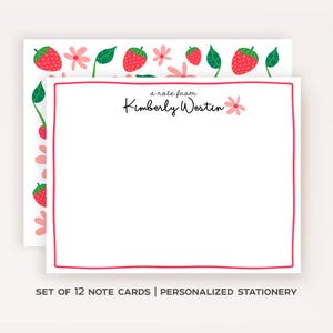 May include: White note cards with a pink border and strawberry and flower illustrations. The text "a note from Kimberly Westin" is printed on the card. The words "SET OF 12 NOTE CARDS | PERSONALIZED STATIONERY" are printed at the bottom.