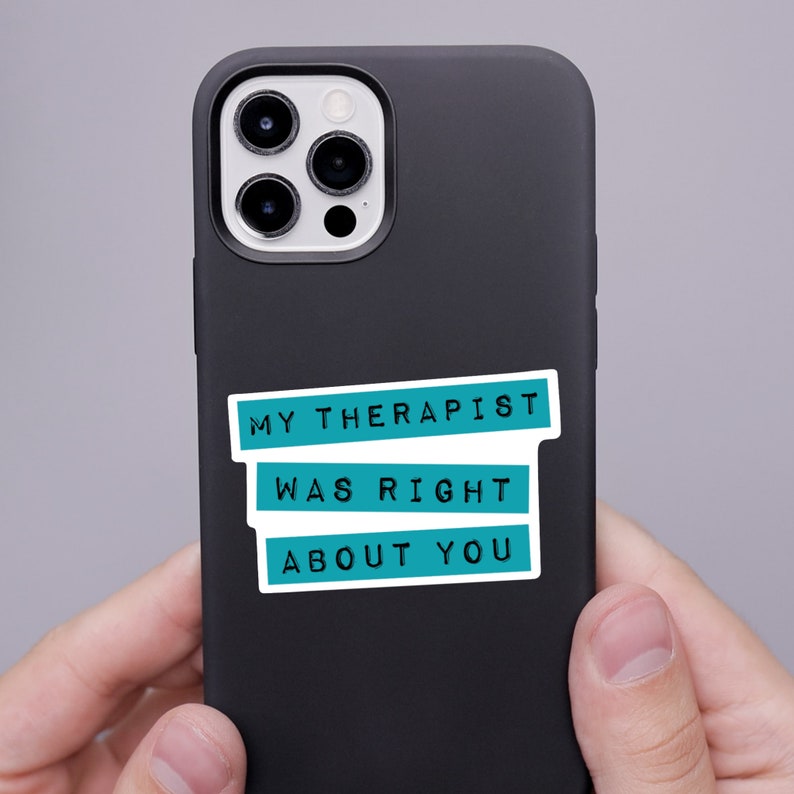 May include: A matte black smartphone case featuring a rectangular sticker with three teal horizontal bars. The text in black capital letters reads MY THERAPIST WAS RIGHT ABOUT YOU, with each line of text contained within its own teal bar.