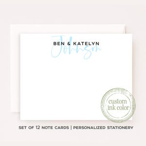 May include: A white note card with a matching envelope featuring the text BEN & KATELYN in black sans-serif font above the name Johnson in a light blue script font. A circular stamp graphic with the text custom ink color is visible.