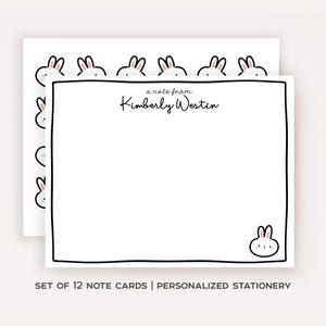May include: A set of white rectangular note cards featuring a black hand-drawn border and a small cartoon rabbit in the bottom right corner. The text reads a note from Kimberly Westin in black script. The cards have a repeating rabbit pattern.