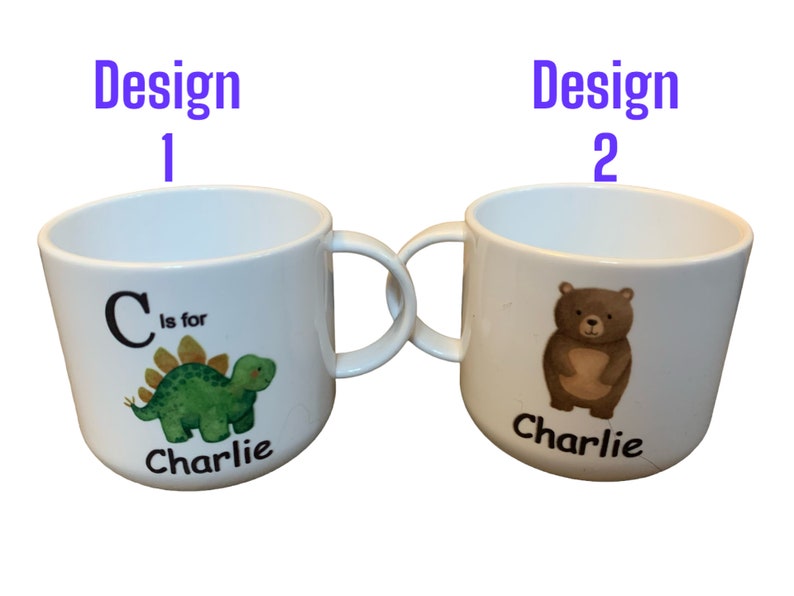 Op de afbeelding: Twee witte keramische bekers met handvatten. De beker links heeft een groene dinosaurus met de letter C en de tekst "C is for Charlie". De beker rechts heeft een bruine beer met de tekst "Charlie".