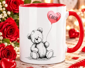 Op de afbeelding: Een witte keramische mok met een felrode binnenkant en handvat. De buitenkant toont een zwart-witte schets van een zittende teddybeer die een touwtje vasthoudt dat verbonden is met een roze aquarel hartballon met de naam CAROL in zwarte letters.